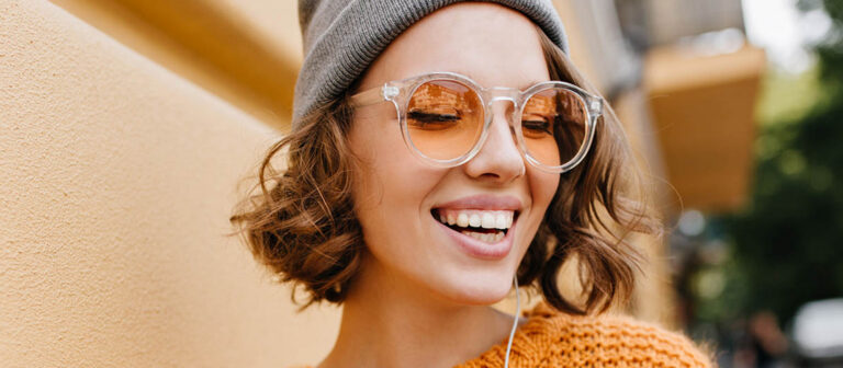 a woman with sunglasses smiling listening to music