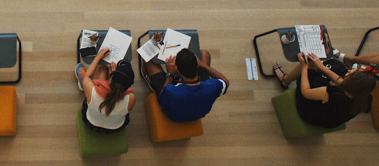 people sitting at little tables writing on paper