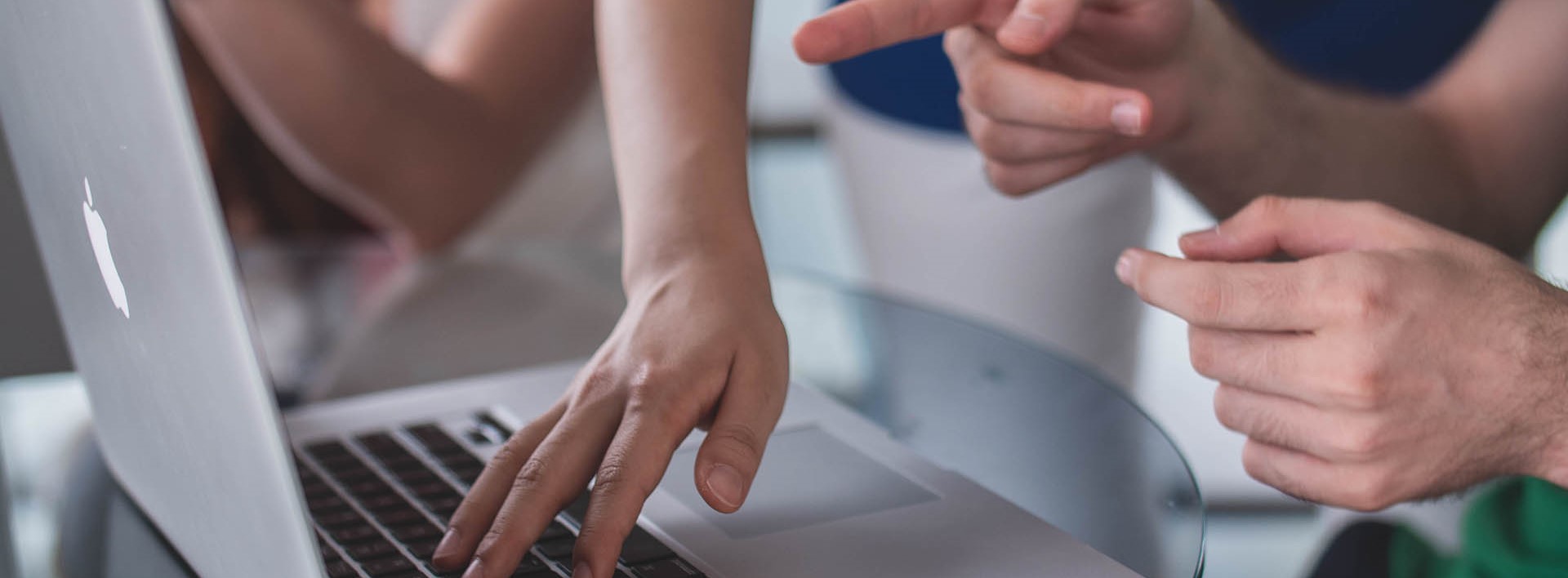A view of the hands of people operating a laptop and collaborating on a atrategy