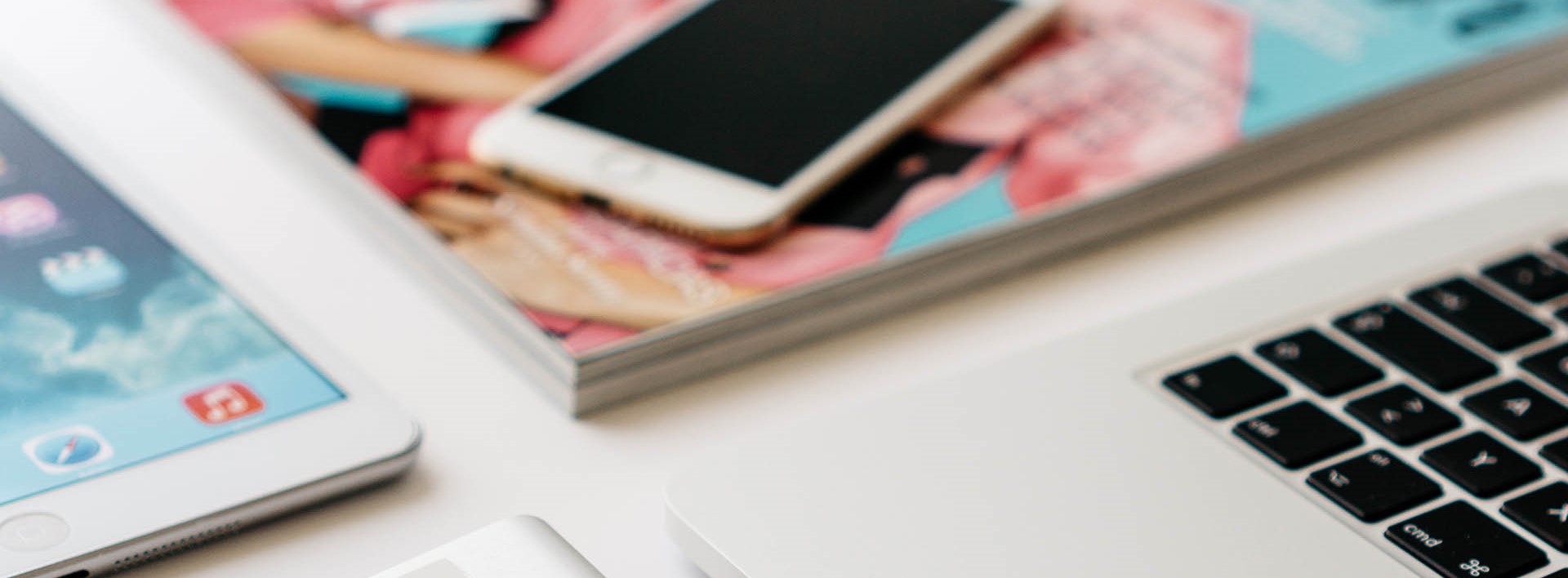 laptop with magazine and phone on a desk