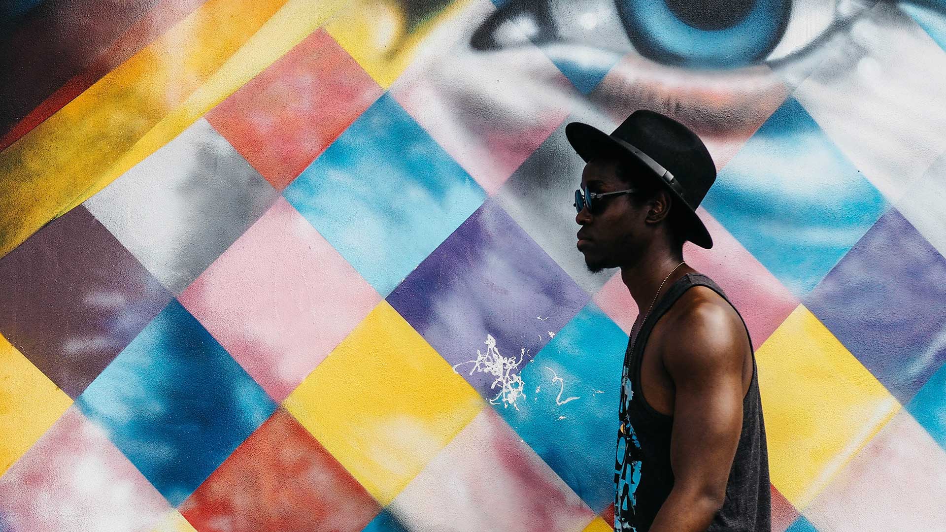 man walking past a colourful wall