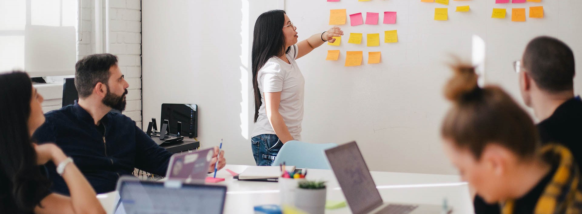 woman sticking sticky notes on a whiteboard in a meeting