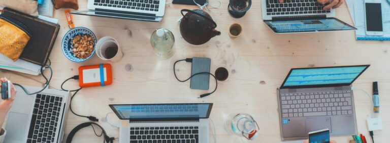 desk with laptops, coffee mugs