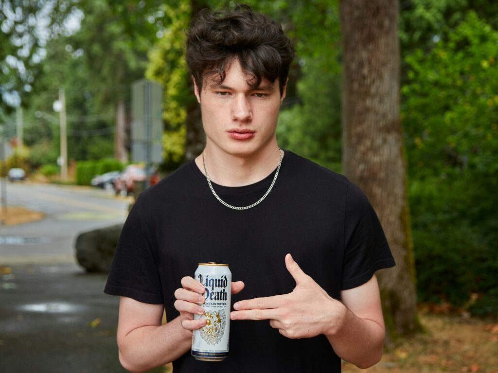 a guy holding a liquid death can