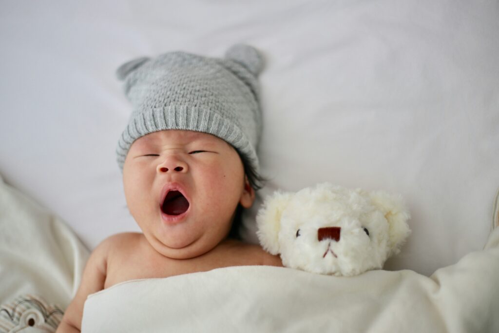 baby yawning with a soft toy