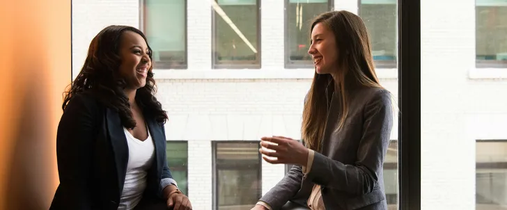 two women sitting near a window and smiling