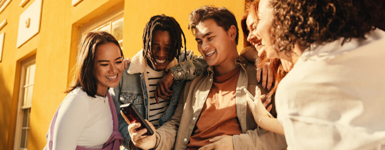 group of people looking at a phone and laughing and smiling