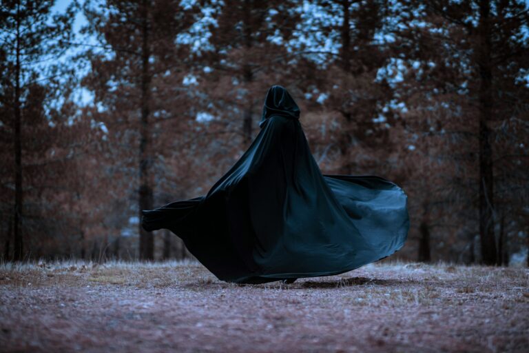 person with a cloak in the woods