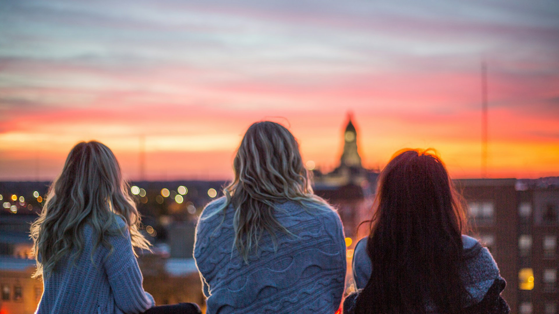 Three women watching a sunset together.