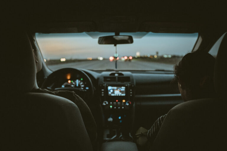 Two people inside a car at dusk.