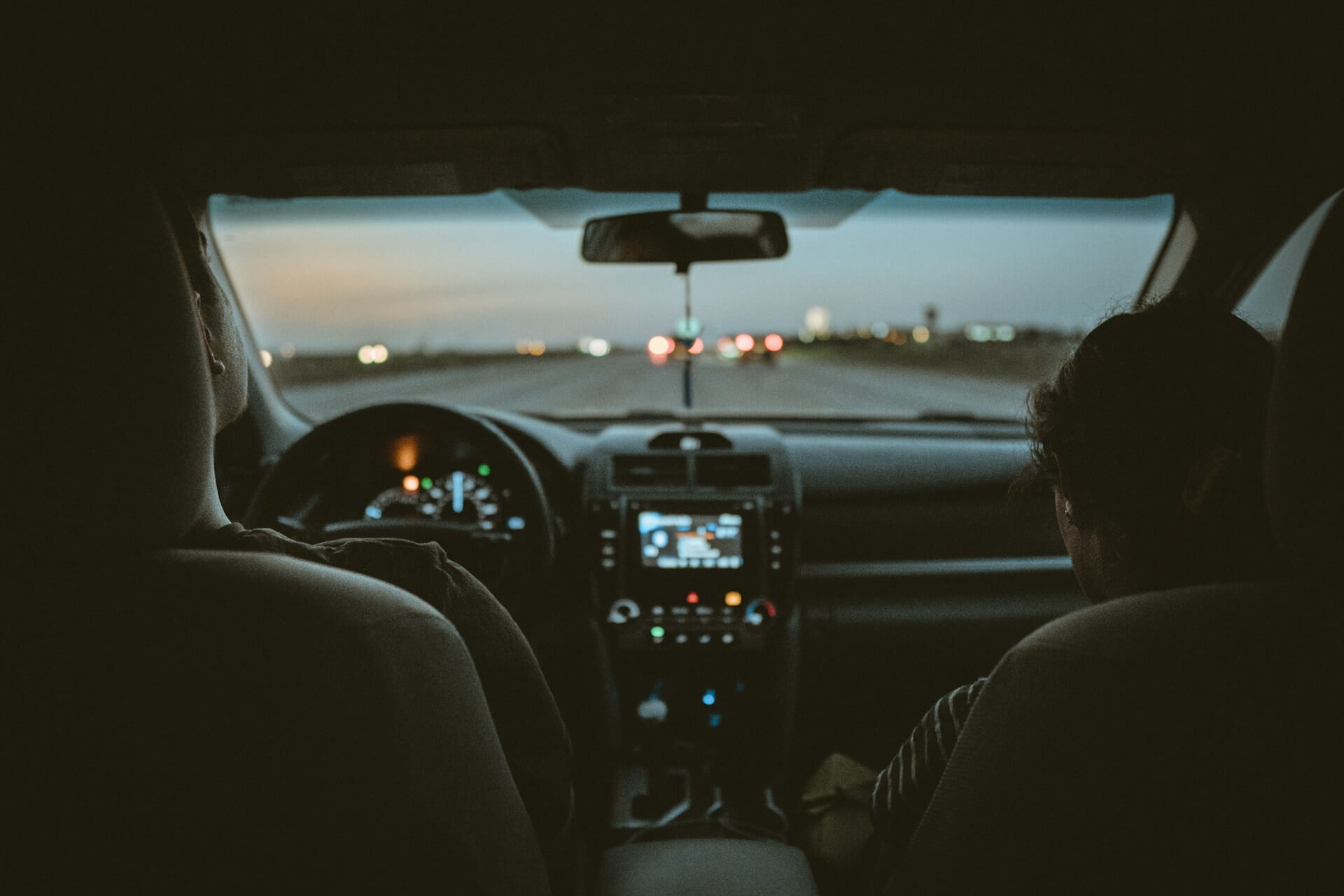 Two people inside a car at dusk.