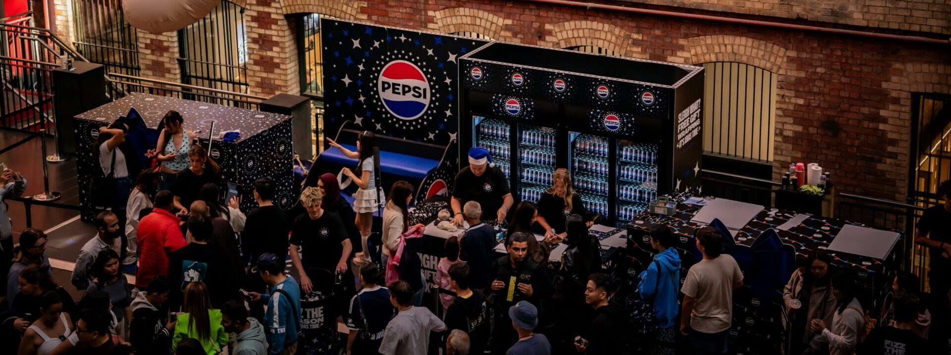 A crowd of people gather by a Pepsico stand
